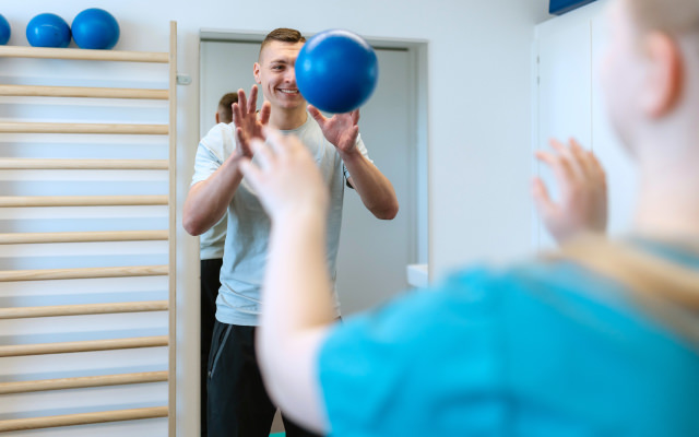 Patient fängt Ball im Therapieraum